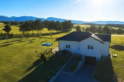 a small white house in a field with a boat at Vila Anamari in Livno