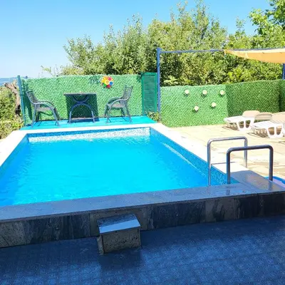 a small swimming pool with two chairs and a umbrella at VIKENDICA GARFILD SA BAZENOM i SAUNOM BANJA LUKA in Banja Luka