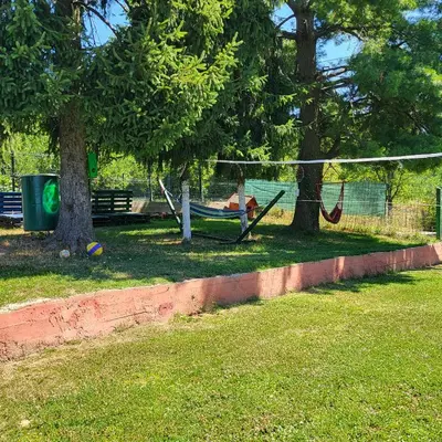 a person laying in a hammock in a park at VIKENDICA GARFILD SA BAZENOM i SAUNOM BANJA LUKA in Banja Luka