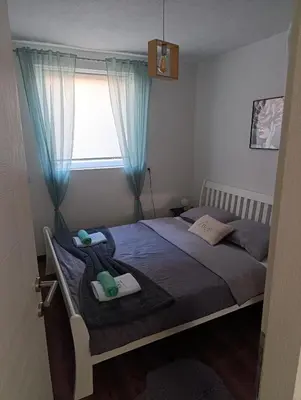a bedroom with a bed with blue curtains and a window at Apartman EDEN in Jajce