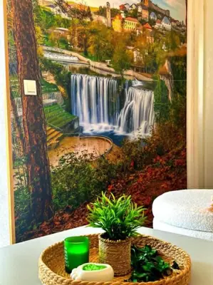 a painting of a waterfall on a wall next to a table at Apartman EDEN in Jajce