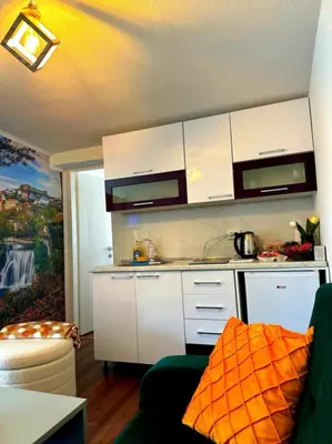 a kitchen with white cabinets and an orange pillow at Apartman EDEN in Jajce