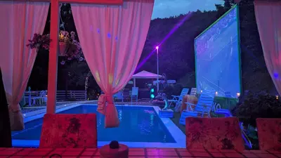 a swimming pool with pink curtains and a projection screen at Nature Neno in Visoko