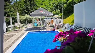 a person sitting next to a swimming pool with an umbrella at Nature Neno in Visoko