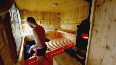 a man standing inside of a wooden sauna at Nature Neno in Visoko