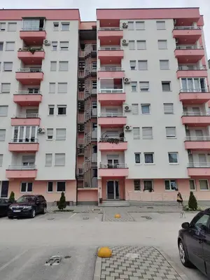 an apartment building with red balconies and a parking lot at Apartman IDEA Tuzla in Tuzla