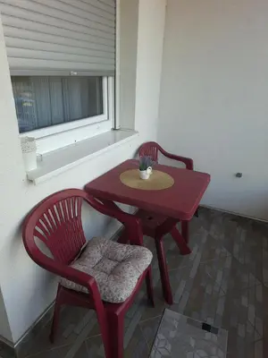 a red table and chair next to a window at Apartman IDEA Tuzla in Tuzla