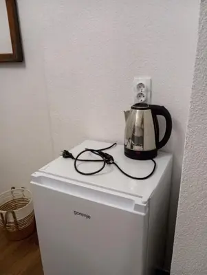 a tea kettle and glasses sitting on top of a refrigerator at The Orchid in Jajce