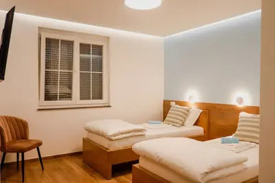 a room with two beds and a chair and a window at Villa Ali in Illidža
