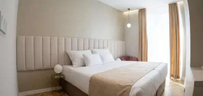 a bedroom with a bed with white sheets and a window at Lala in Bosanska Krupa