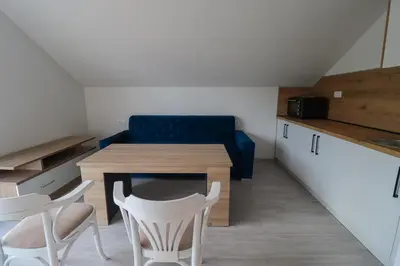 a living room with a couch and a table and chairs at Tadic apartments and rooms by the shore of Rama Lake in Prozor