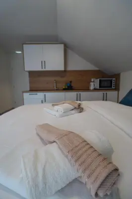a white bed with two towels on top of it at Tadic apartments and rooms by the shore of Rama Lake in Prozor