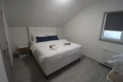 a bedroom with a white bed with two books on it at Tadic apartments and rooms by the shore of Rama Lake in Prozor