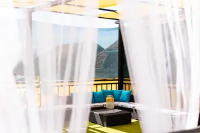 a room with white curtains and a table with a couch at Khalilah Apartment 1 in Bihać