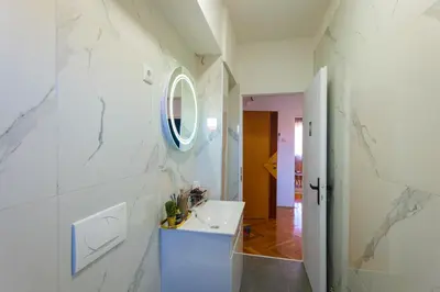 a white bathroom with a sink and a mirror at Khalilah Apartment 1 in Bihać