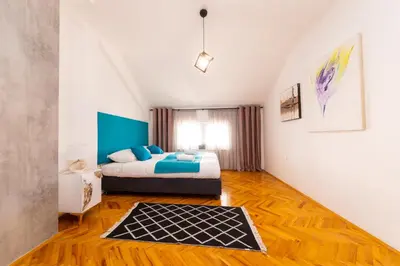 a bedroom with a bed and a rug on a wooden floor at Khalilah Apartment 2 in Bihać