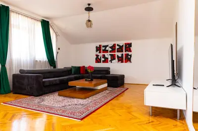 a living room with a black couch and a tv at Khalilah Apartment 2 in Bihać