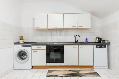 a kitchen with white cabinets and a washing machine at Khalilah Apartment 2 in Bihać