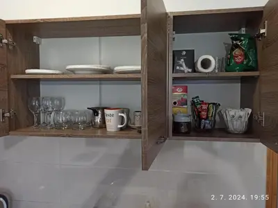 a kitchen shelf with dishes and glasses on it at Apartman Oaza in Doboj