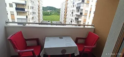 a table and four chairs on a balcony with a window at Apartman Oaza in Doboj