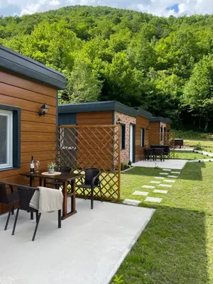 a patio with a table and chairs and a house at Bungalovi izvor Plive 2 in Šipovo