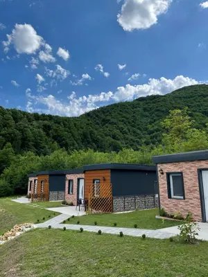 a row of modular homes in front of a mountain at Bungalovi izvor Plive 3 in Šipovo