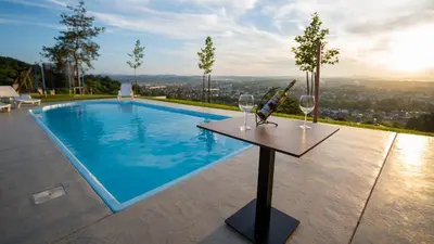two wine glasses on a table next to a swimming pool at Villa, Vikendica - Sunny Hill - jacuzzi, sauna in Banja Luka