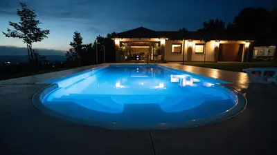 a blue swimming pool in front of a house at night at Villa, Vikendica - Sunny Hill - jacuzzi, sauna in Banja Luka