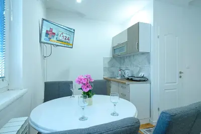 a small kitchen with a white table and two wine glasses at Evergreen Apartments in Visoko