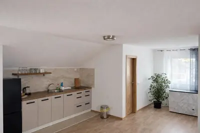 a kitchen with white cabinets and a black refrigerator at Apartmani Sun & Moon in Žepče
