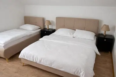 two beds in a bedroom with two lamps on night stands at Apartmani Sun & Moon in Žepče
