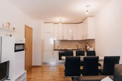a kitchen with white cabinets and a table and chairs at Pronađi svoj mir in Livno