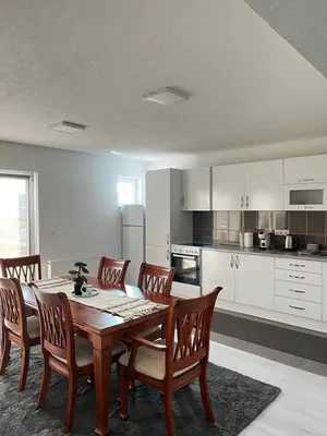 a dining room with a table and chairs and a kitchen at Apartment M&S Gračanica in Gračanica