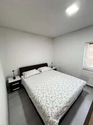 a white bedroom with a bed and a window at Apartment M&S Gračanica in Gračanica