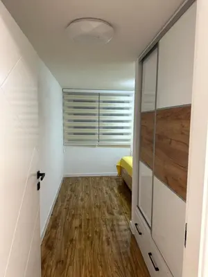 a bedroom with white walls and a wooden floor at JB apartman Živinice in Živinice