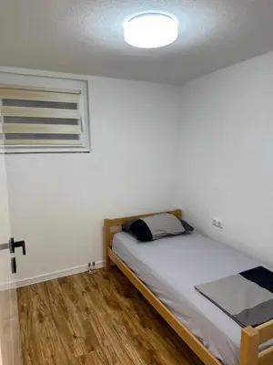 a small bedroom with a bed and a window at JB apartman Živinice in Živinice