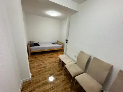 a small room with a bed and chairs in it at JB apartman Živinice in Živinice