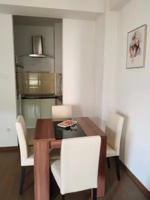 a dining room with a wooden table and white chairs at Apartman IJA in Banja Luka
