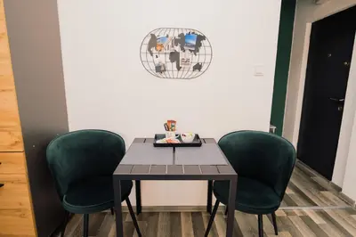 a table with four green chairs and a plate on it at Apartment Vela in Tuzla