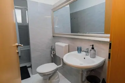 a bathroom with a toilet and a sink and a mirror at Apartment Vela in Tuzla