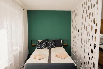 a bedroom with a bed with a green wall at Apartment Vela in Tuzla