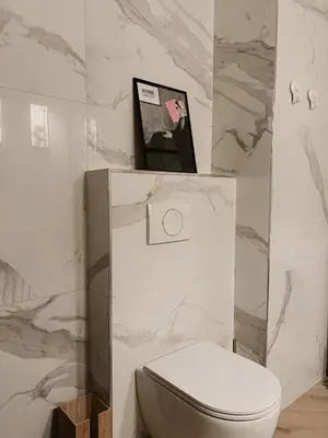 a bathroom with a white toilet and marble walls at Ikigai Penthouse Apartment in Banja Luka