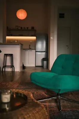a green couch in a living room with a kitchen at Ikigai Penthouse Apartment in Banja Luka