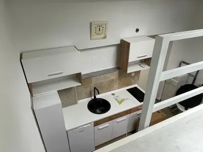 a small kitchen with white cabinets and a sink at Studio apartman Bišće in Bihać