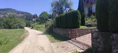 a dirt road with a fence next to a house at Lake House Ceric in Jajce