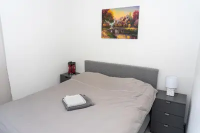 a bedroom with a bed with a picture on the wall at Apartman Kruna in Drvar