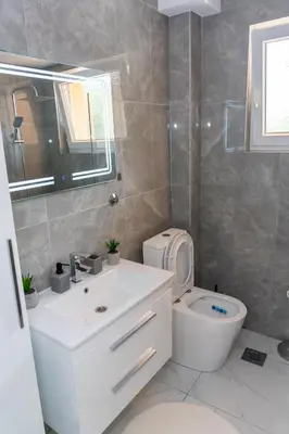 a bathroom with a toilet and a sink and a mirror at Apartman Kruna in Drvar