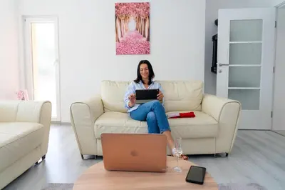a woman sitting on a couch with a laptop at Apartman Kruna in Drvar