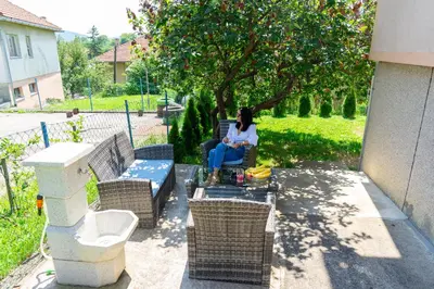 a woman sitting on a patio with a laptop at Apartman Kruna in Drvar