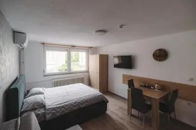 a bedroom with a bed and a table and a window at Apartmani Vesto in Banja Luka